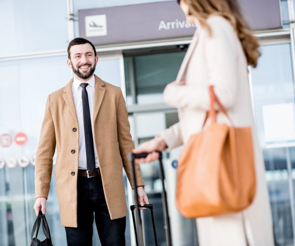 Business woman meeting male business partner near the airport entrance outdoors